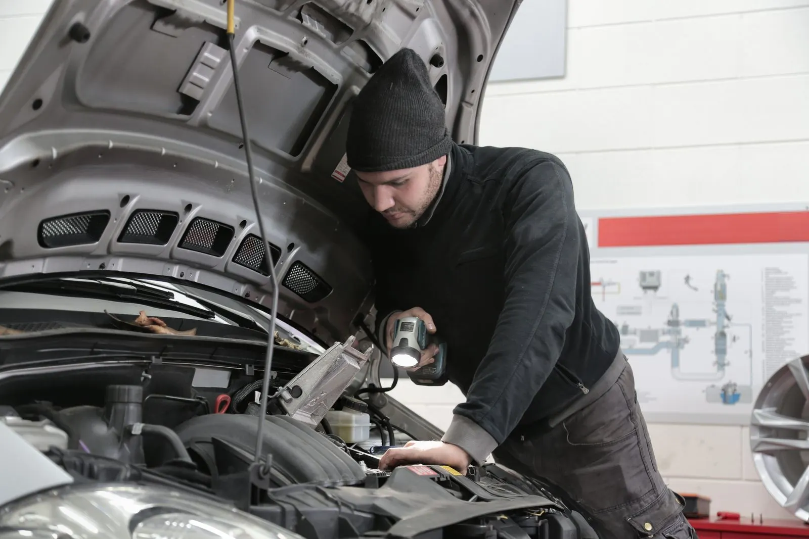Two technicians working beneath a car raised on a hoist