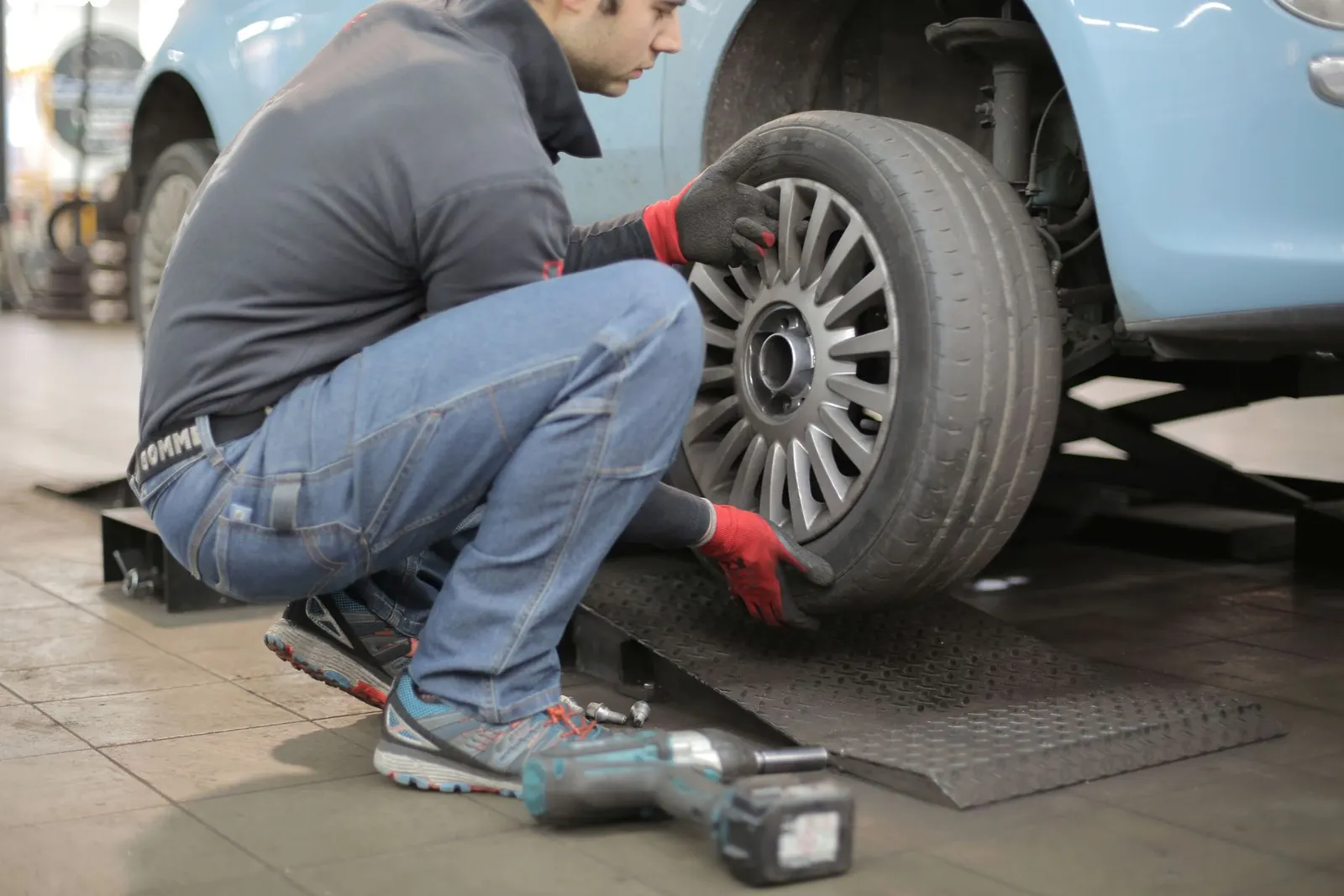 Two mechanics working under a car raised on a workshop hoist